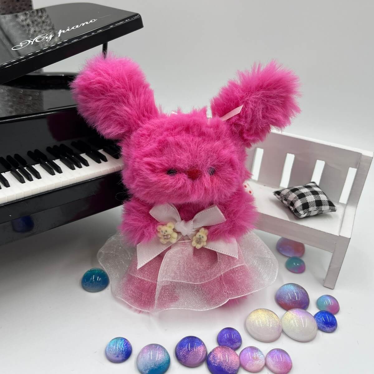 Pink fluffy toy with a bow in front of a piano